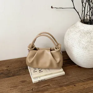 Detailansicht der beigen Falten-Handtasche aus weichem mattem Leder auf einem Holzschreibtisch