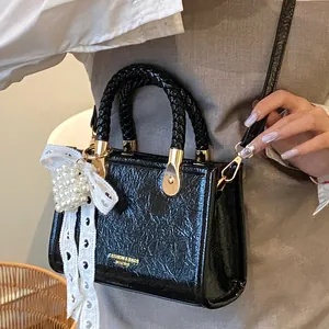 Glanzende zwarte geplooide mini crossbodytas met geweven handvat en parelbedeltje