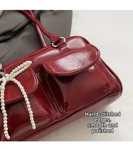 Detail of burgundy Boston bag with pearl beads and hand-stitched smooth edging