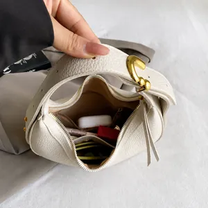 Détail d'un sac hobo en cuir grainé montrant un intérieur spacieux avec poche zippée