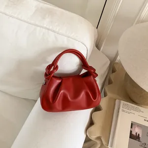 Detail der roten gerafften Cloud-Tasche mit Knotengriff auf einem weißen Sofa