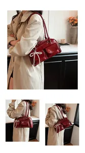 Detail view of burgundy glossy Boston bag with pearl bow charm and twin front pockets