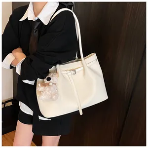 Side view of a beige woven tote bag with a plush puppy charm and long shoulder straps