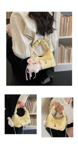 Detail van lichtgele halvemaanvormige tas met scrunchie-handvat, strik en beerbedel