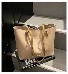 Detail of minimalist cream tote bag with contrast tan handles on a book background