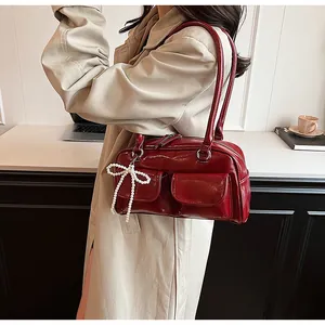 Detail of burgundy leather Boston bag with pearl bow pendant and dual front pockets