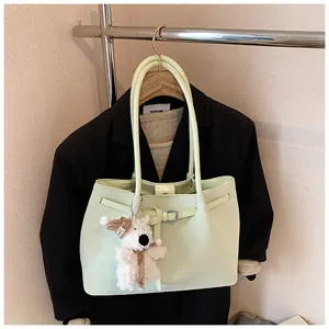 Detail view of light green woven tote bag with a cute white plush bear charm hanging