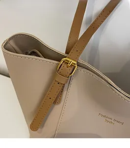 Detailed macro view of golden metal buckle and stitching on the beige leather tote bag