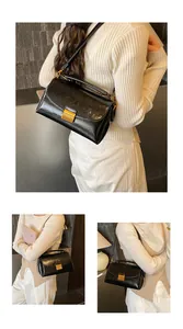 Détail de la texture en cuir verni noir et de la boucle dorée sur un sac carré