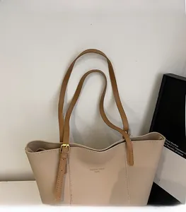 Detail showing the adjustable brown strap and gold stamped text on beige tote bag