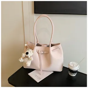 Detail of light pink tote bag featuring woven texture and a cute plush bear charm accessory