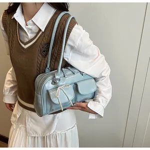 Detail view of sky blue Boston bag featuring front pockets and pearl bow charm