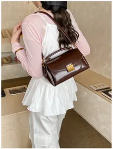 Détail du sac bandoulière vintage marron foncé en similicuir avec boucle dorée
