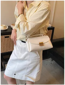 Gros plan d'un sac à bandoulière en cuir verni blanc crème avec boucle dorée