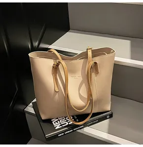 Detail showing high-capacity beige leather tote bag with elegant shoulder straps on steps
