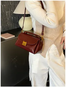 Vue détaillée d'un sac à main vintage en cuir rouge foncé avec fermoir doré sur un modèle