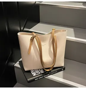Detail of cream tote bag with brown straps placed on books for a premium aesthetic look
