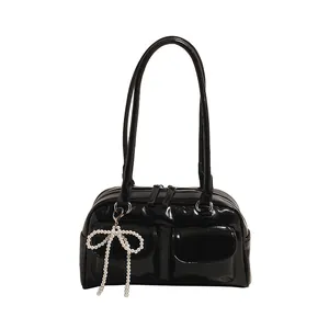 Glossy black Boston shoulder bag with dual front pockets and pearl bow charm detail