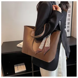 Detail of dark brown tote bag with decorative star pattern scarf and sleek leather finish