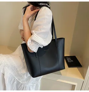Detail of minimalist black matte leather tote bag with elegant gold Fashion Trend logo