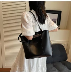 Detailed view of the large black tote bag on a model wearing a white dress