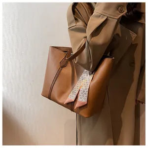 Detail of caramel brown leather tote bag with a decorative geometric silk scarf on handle