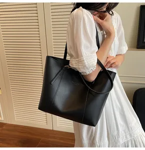 Detail of black leather tote bag with gold buckle and fashion trend text on smooth surface