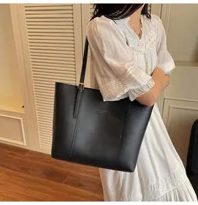 Detail view of the black leather tote bag featuring gold lettering and adjustable shoulder strap