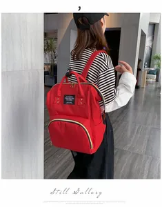 Red waterproof diaper backpack with large capacity and durable straps shown on a model