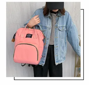 Pink waterproof diaper backpack showing golden zippers and living traveling share label