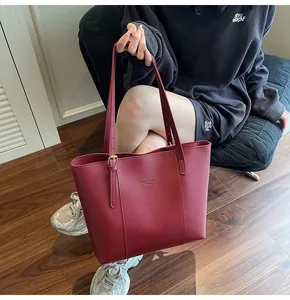 Detail of deep red faux leather tote bag with fine texture and gold hardware accents