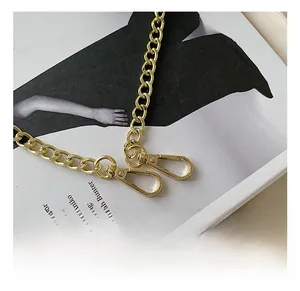 Detail showing the shiny golden metal chain strap with two lobster claw clasps on a magazine