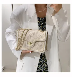 Detail of woven straw shoulder bag featuring pearl accents and gold square buckle