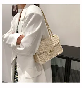 Detail view of the cream woven shoulder bag with pearl trim and gold metal chain strap