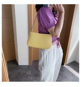Detalle de un bolso baguette amarillo brillante con cadena de plata en una modelo