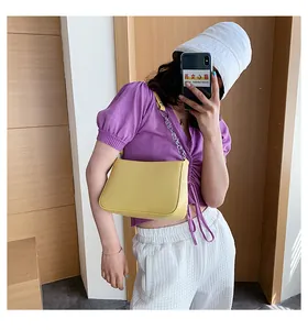 Bolso de hombro baguette amarillo vibrante con cadena plateada visto en un modelo