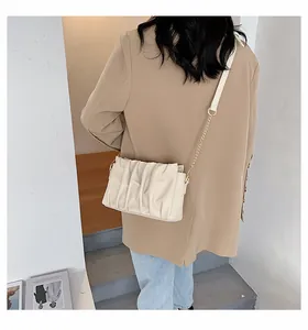 Detailed back view of a creamy white pleated crossbody bag with a gold chain strap
