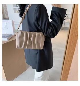 Detail of beige pleated cloud bag with unique woven shoulder strap and gold hardware hooks