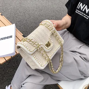 Straw woven crossbody bag with pearl trim and gold chain strap for elegant summer vacation look