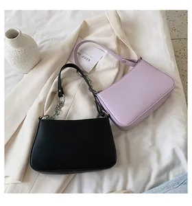 Vista detallada de bolsos baguette negros y morados con correas de cadena sobre tela