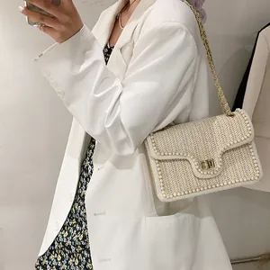 Chic woven shoulder bag with pearl trim and gold chain strap shown on a model