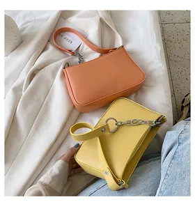 Detalle de bolsos baguette de cuero naranja y amarillo de moda con correa de cadena