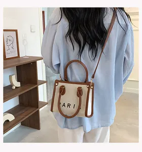 Detail of canvas tote bag with brown leather handles and Paris print lettering