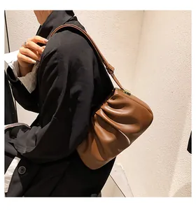Détail d'un sac à bandoulière plissé marron en cuir mat avec fine sangle sur un modèle