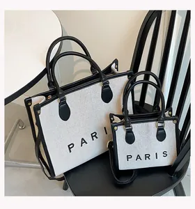 Detail of canvas tote bags with black leather trim and PARIS text on the front