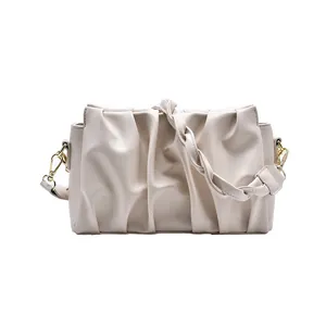Chic beige ruched dumpling bag with woven strap and gold hardware on white background
