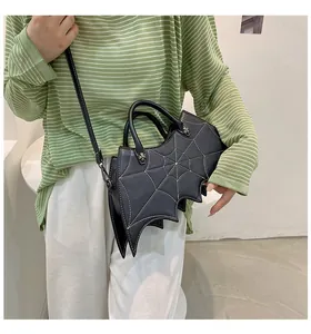 Close-up of gothic black bat-wing handbag with white spider web stitching on model