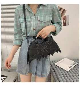 Detail of bat-shaped black PU leather bag with white spider web stitching and charms
