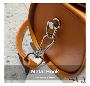 Detailed close-up of a silver lobster clasp on a stylish caramel leather cylinder bag