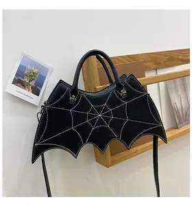 Detail of bat-shaped leather bag featuring spiderweb stitching and silver cross hardware